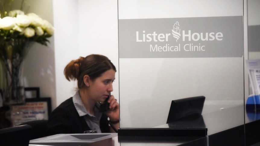 A receptionist speaks on the phone at a desk at Lister House Medical Clinic.