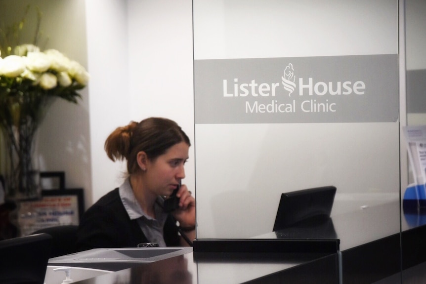 A receptionist speaks on the phone at a desk at Lister House Medical Clinic.