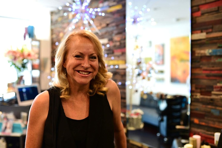 Adult hairdressing apprentice Veronica Ford smiles in her workplace, a hair salon in Brisbane.