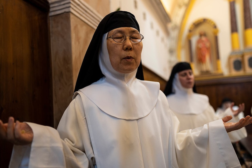 Una monja cierra los ojos y reza en la iglesia. 
