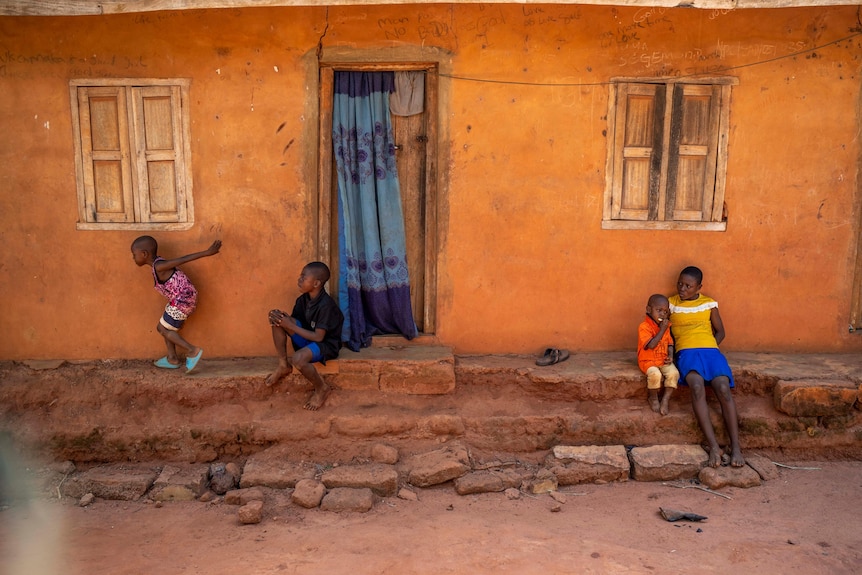 Four children play and sit outside their home in Nigeria. 