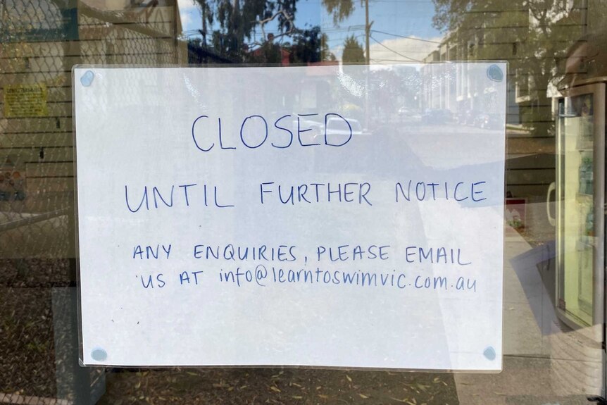 A sign on a glass door says the swimming school is closed until further notice.