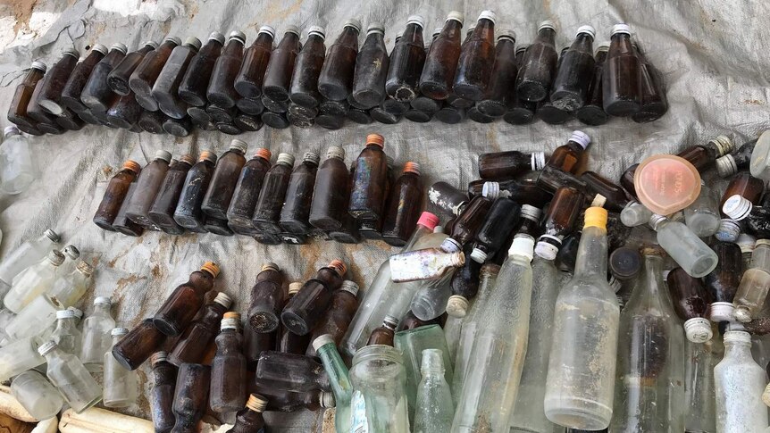 A photo of glass bottles laid out on a tarpaulin.