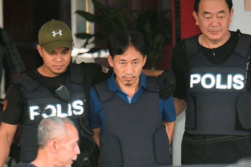 Ri Jong Chol leaves a Malaysian police station with police.
