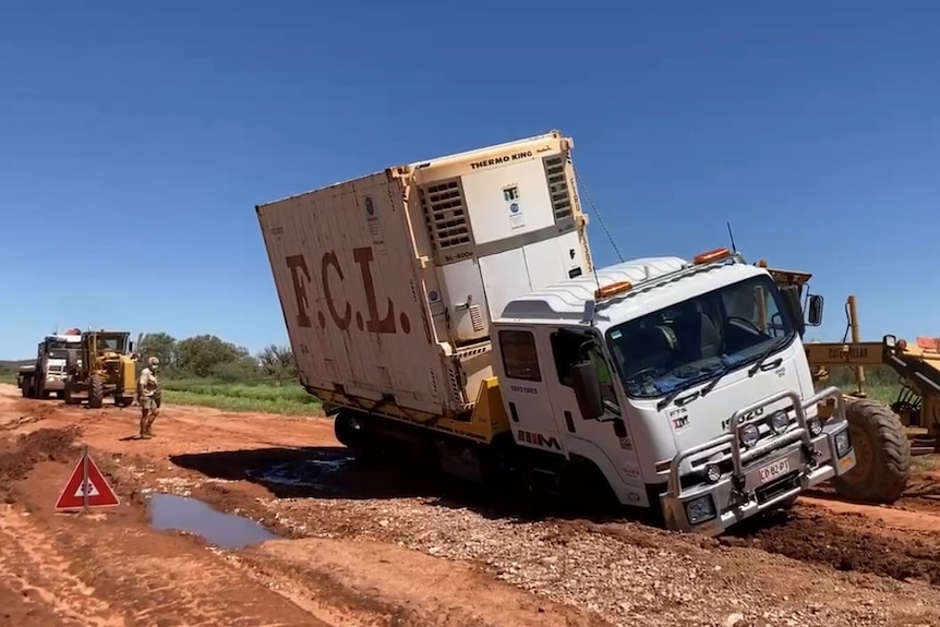 tractor pulling truck bogged on a dirt road