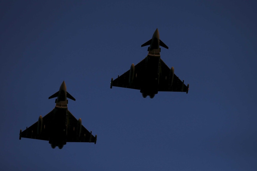 Two RAF Typhoon fighter jets fly through a blue sky