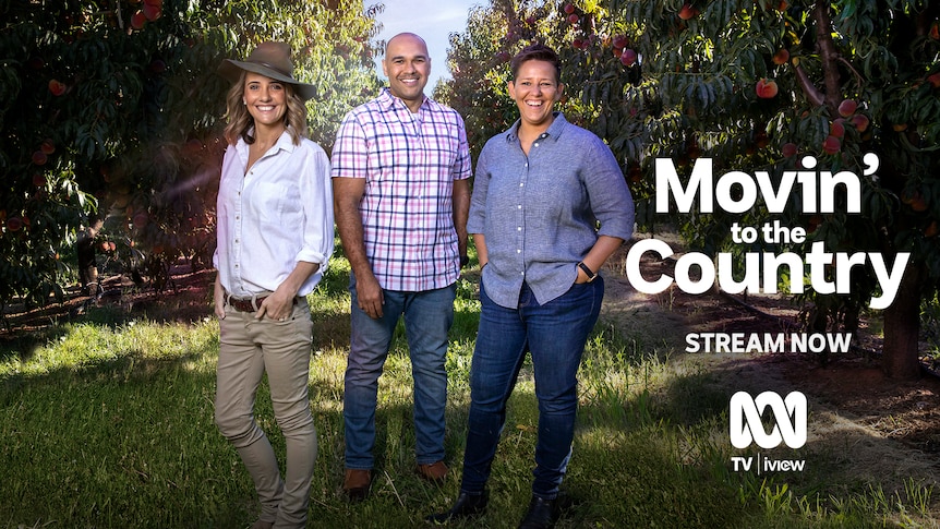 Two women and a man stand smiling in a peach orchard, with 'Movin' To The Country' written beside them