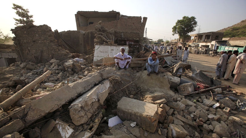 Villagers sit amidst the rubble of their destroyed shops hit by a suicide bomb attack a day earlier.