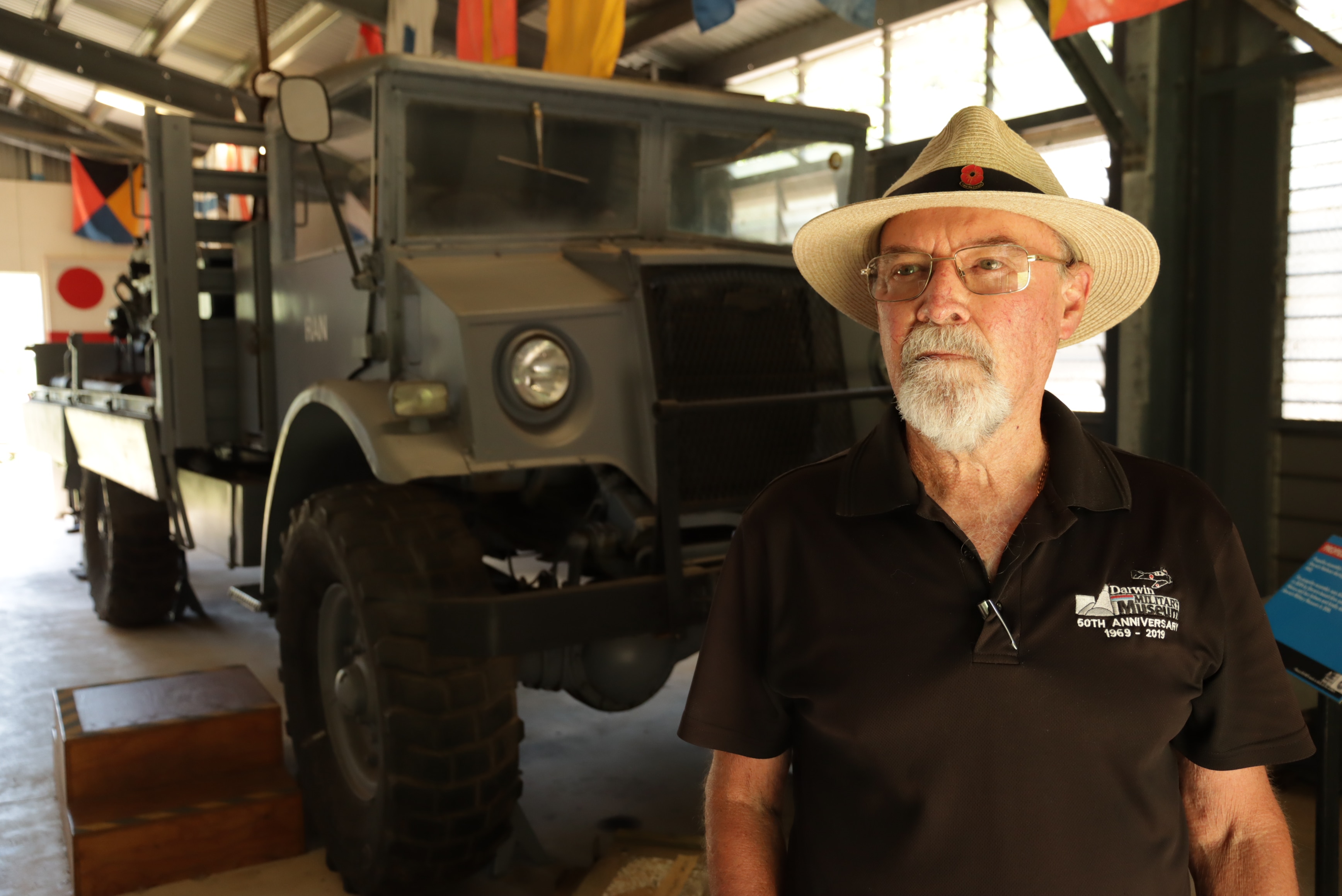 a man wearing a hat in front of an old ww2 tank