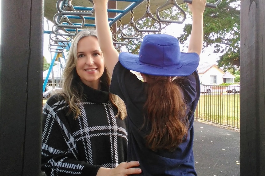 A woman with her daughter at a playground.