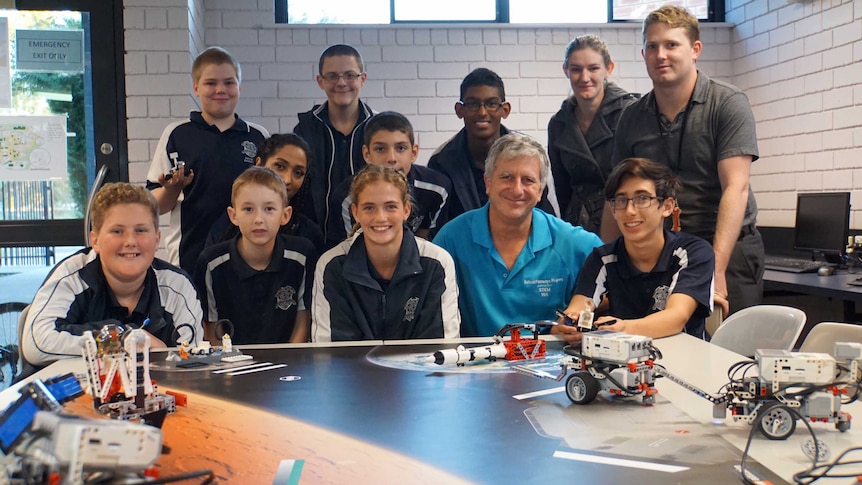 A group of school students with their teacher and robots they have made.