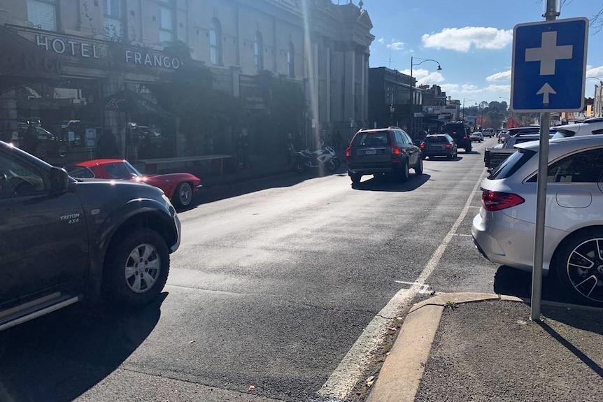 A line of cars queue along a small town's main street