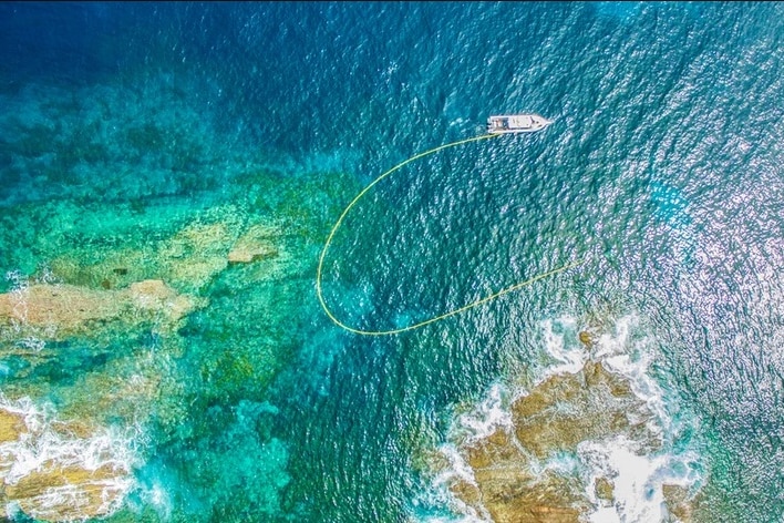 An aerial photo shows a boat and blue water
