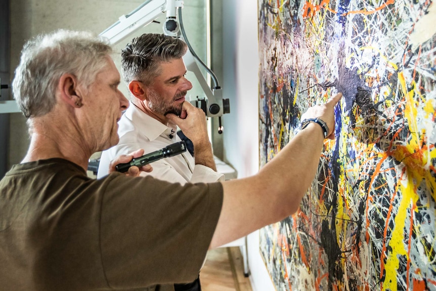 Two men looking at Jackson Pollack's artwork Blue Poles.