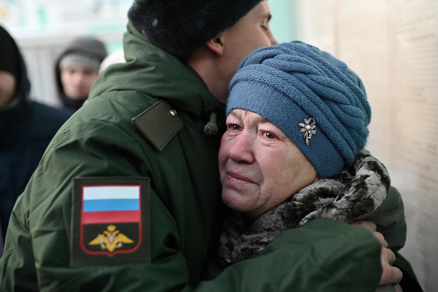 A woman cries as she hugs a man dressed in uniform