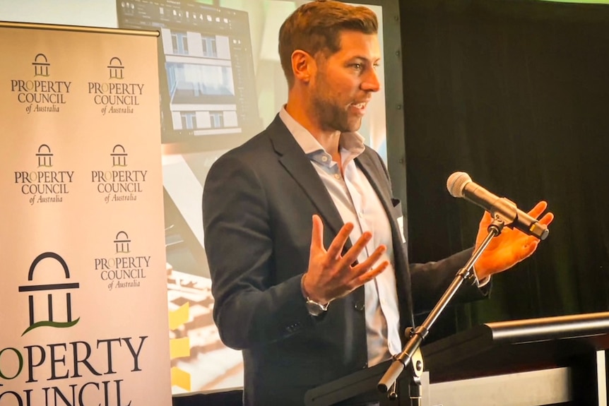 Man in a suit speaking at a microphone