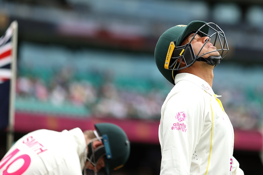 Australia batter Usman Khawaja looks up to the sky as he walks onto the field for a Test cricket match. Steve Smith is behind.