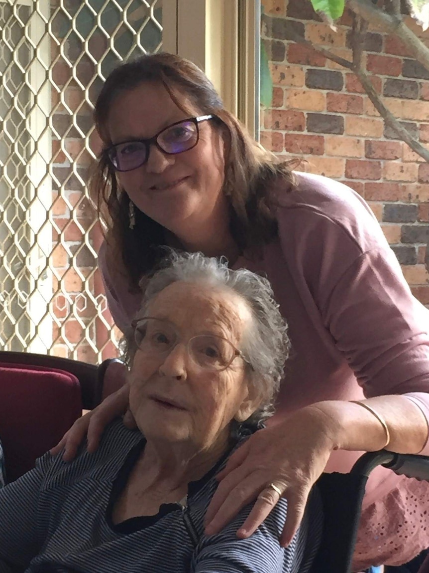 Leone Corrigan sits in a wheel chair with her daughter Bernadette Quigley standing behind her leaning over with arms over shoul