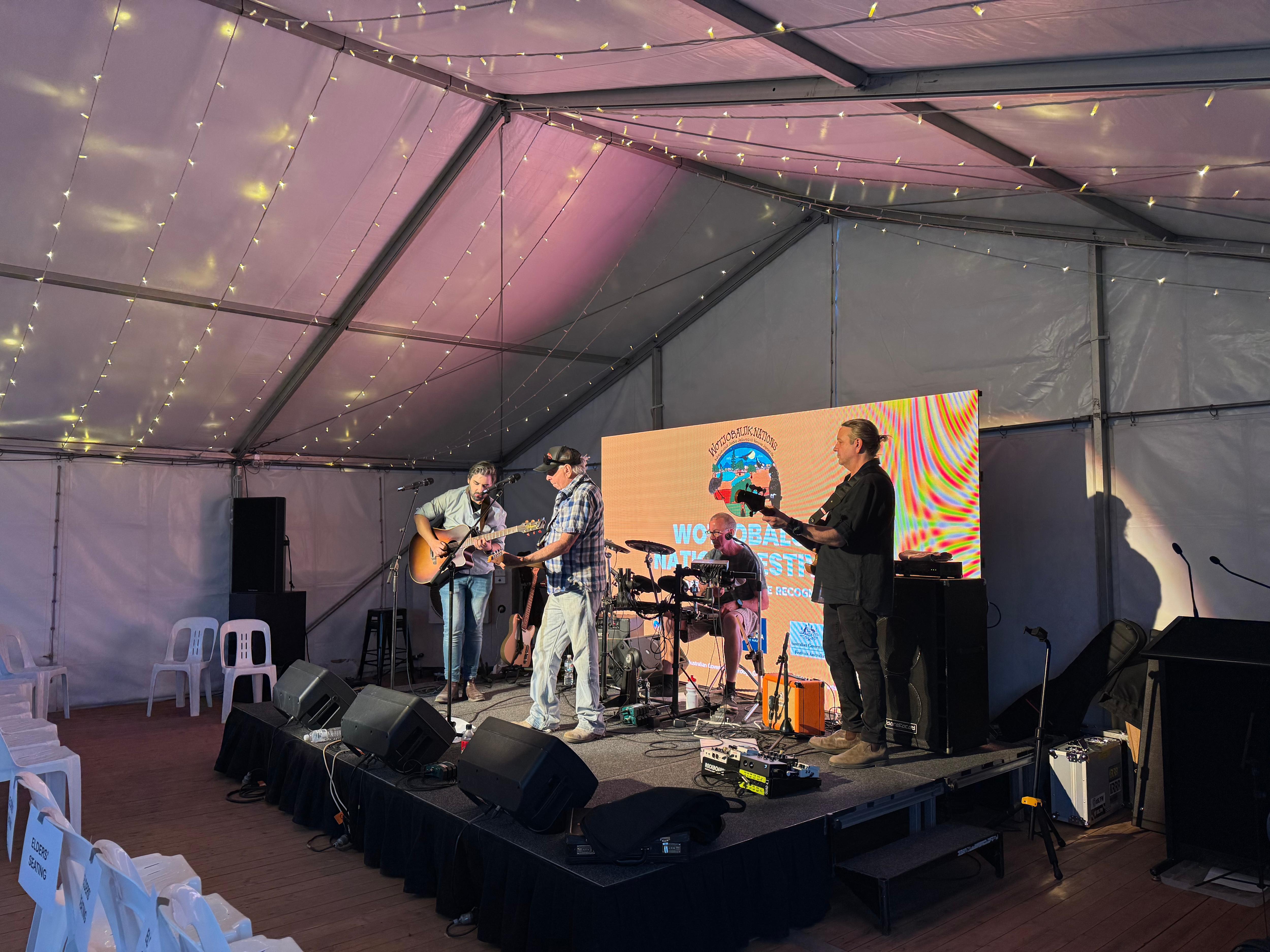 uma banda composta por 4 homens tocando guitarra, bateria e cantando e subindo no palco