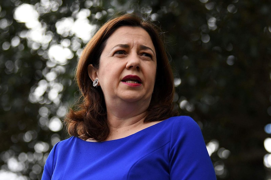 A woman dressed in a deep blue dress — Annastacia Palaszczuk — speaks to the media.