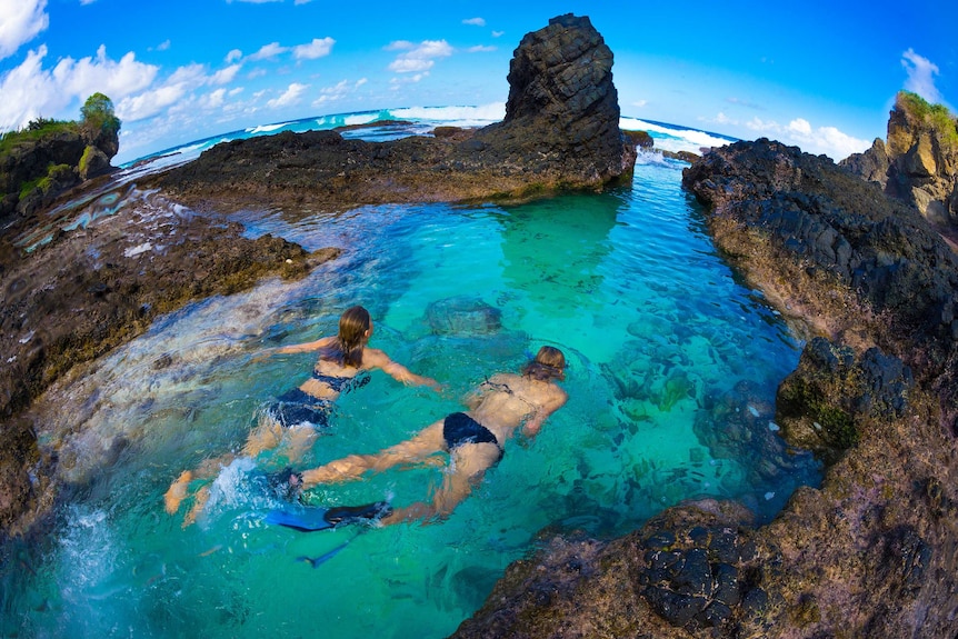 Two girls swim among reefs at Dolly Beach on Christmas Island.