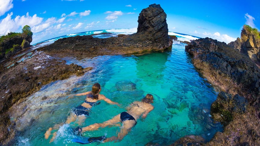 Two girls snorkelling in reefs.