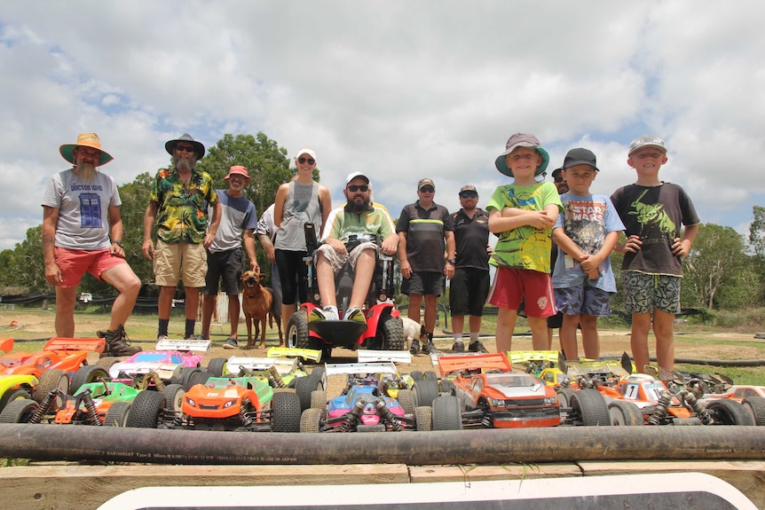 A group of a dozen people stand on a track