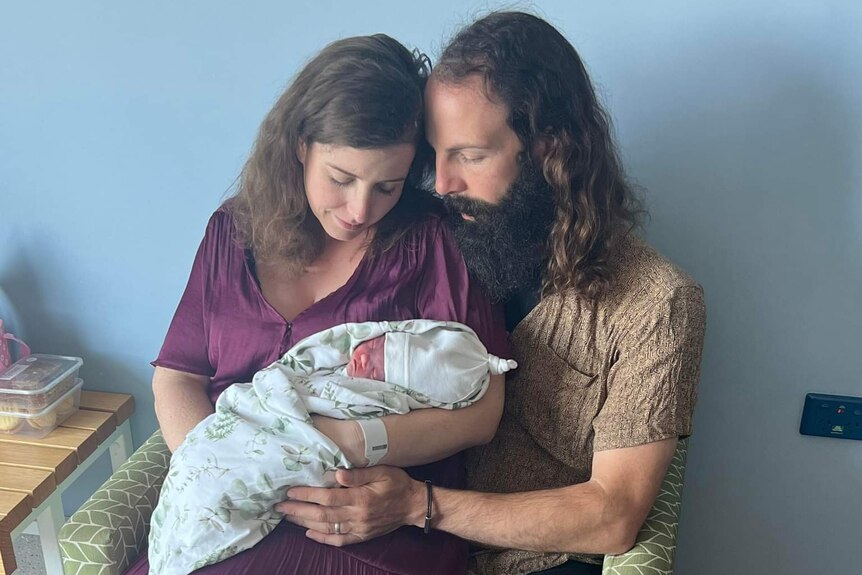 A photo of a couple holding a baby 