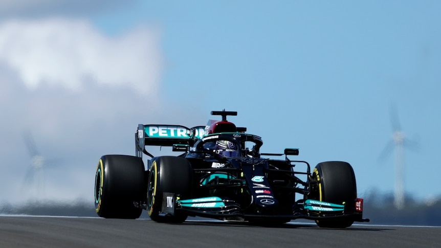 A Formula One car comes over a hill as it does a lap of the track in practice.  