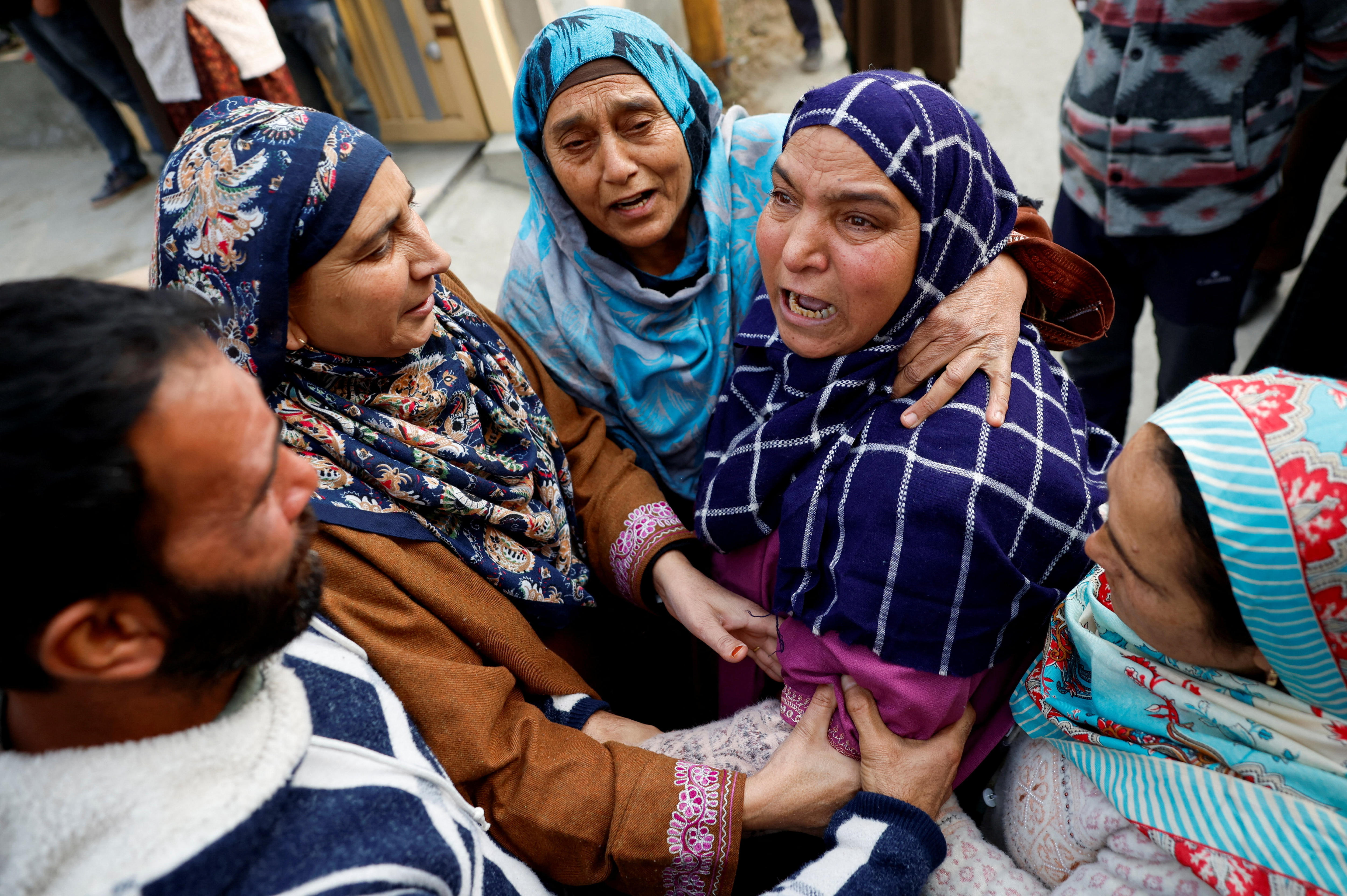 A woman with a look of agony being embraced by three other women and a man.