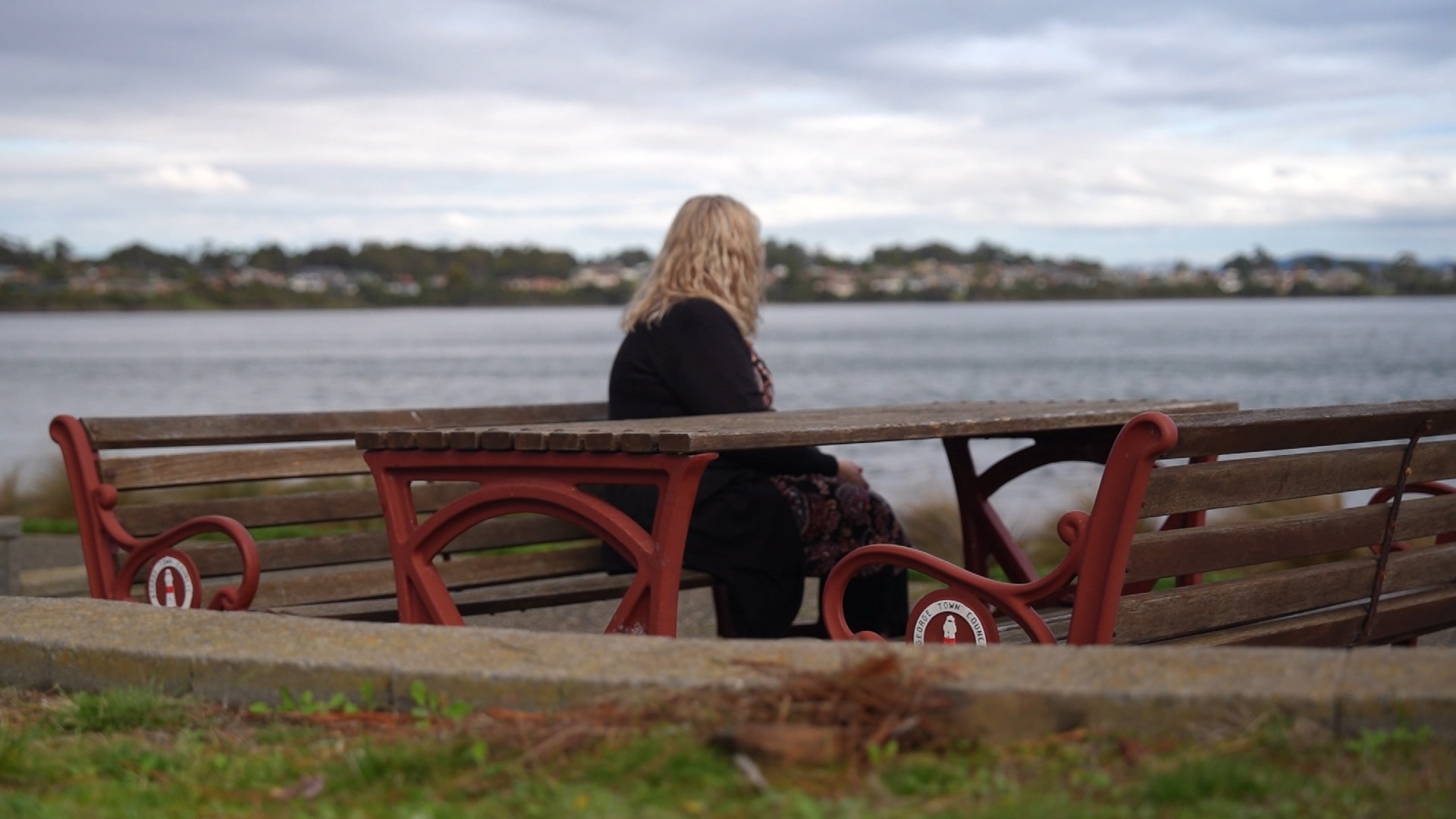A woman sits on a bench on the foreshore