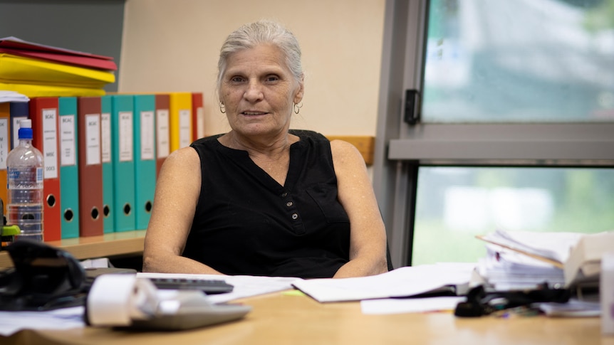 A woman silver hair wearing a black top at an office desk