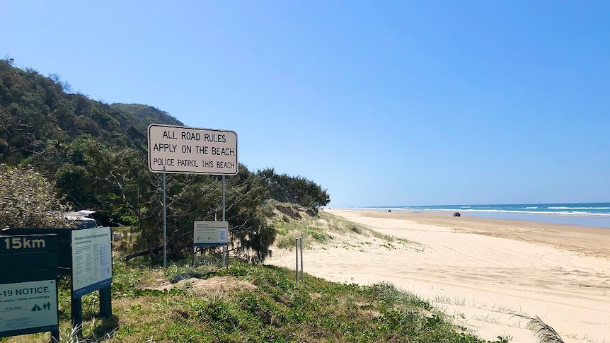 A stretch of beach with a road rules sign