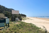 A stretch of beach with a road rules sign