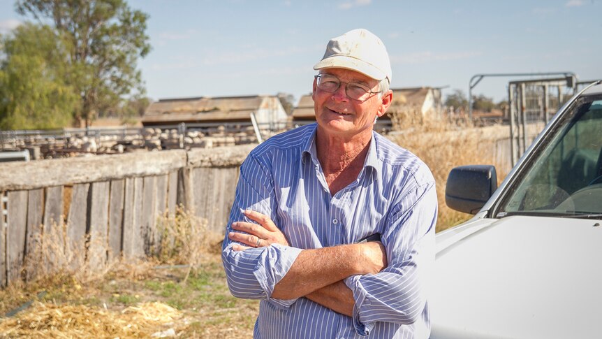 Stock agent Ross Ellis leans on his ute in front of some sheep yards.