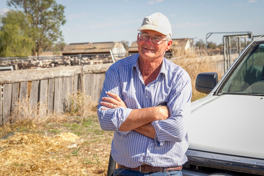 Stock agent Ross Ellis leans on his ute in front of some sheep yards.