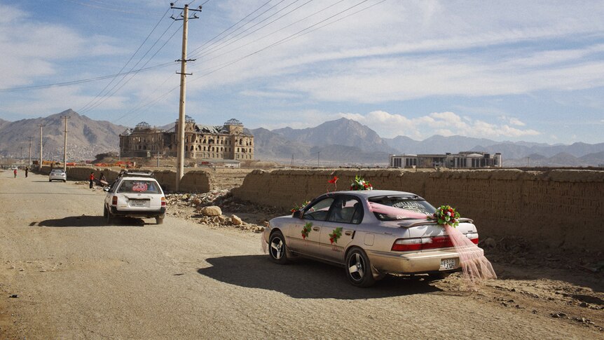 A car decorated for a wedding drives by the King's Palace in Darulaman, just south of Kabul City.