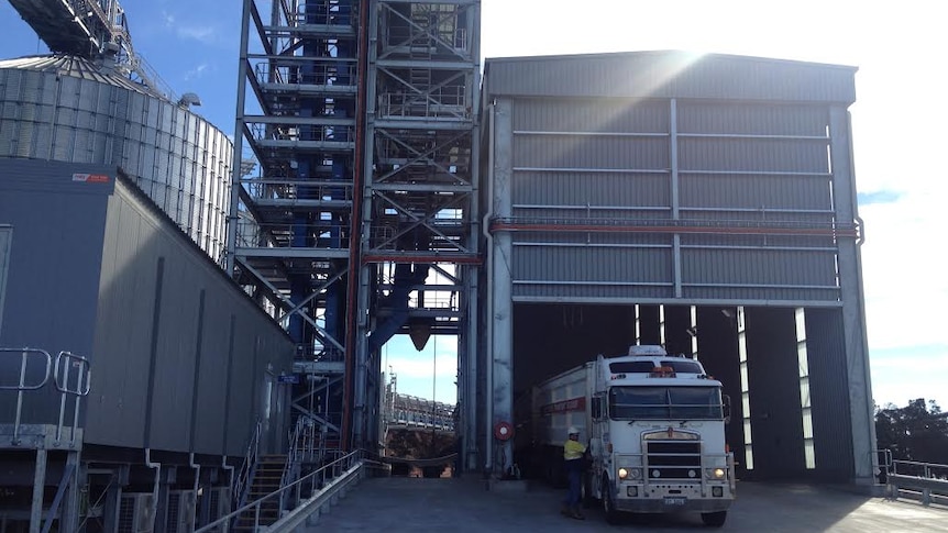 A truck pulls up next to a grain storage area.