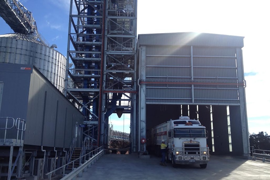 A truck pulls up next to a grain storage area.