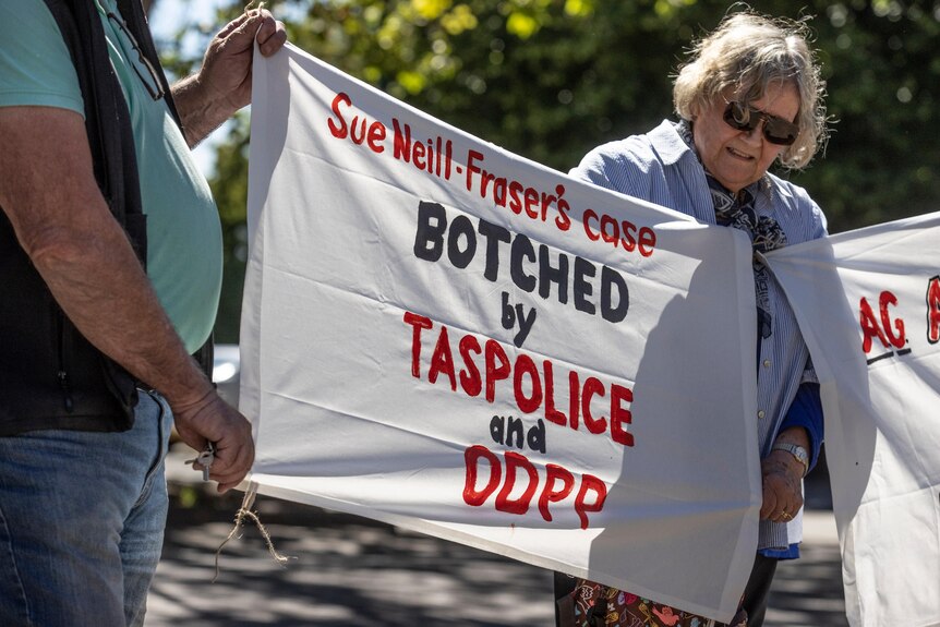 A woman and a man hold a banner reading Sue-Neill Fraser's case botched