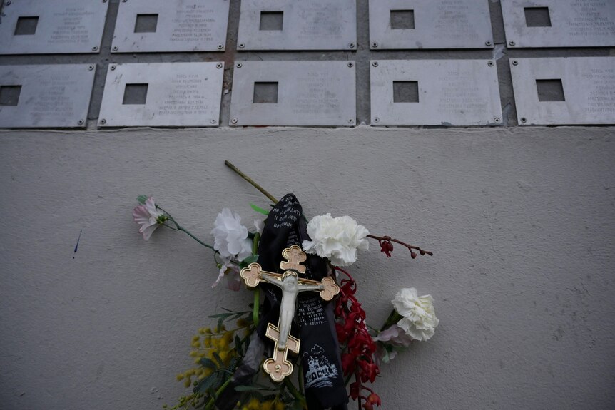 Flowers and a cross under metal plaques.