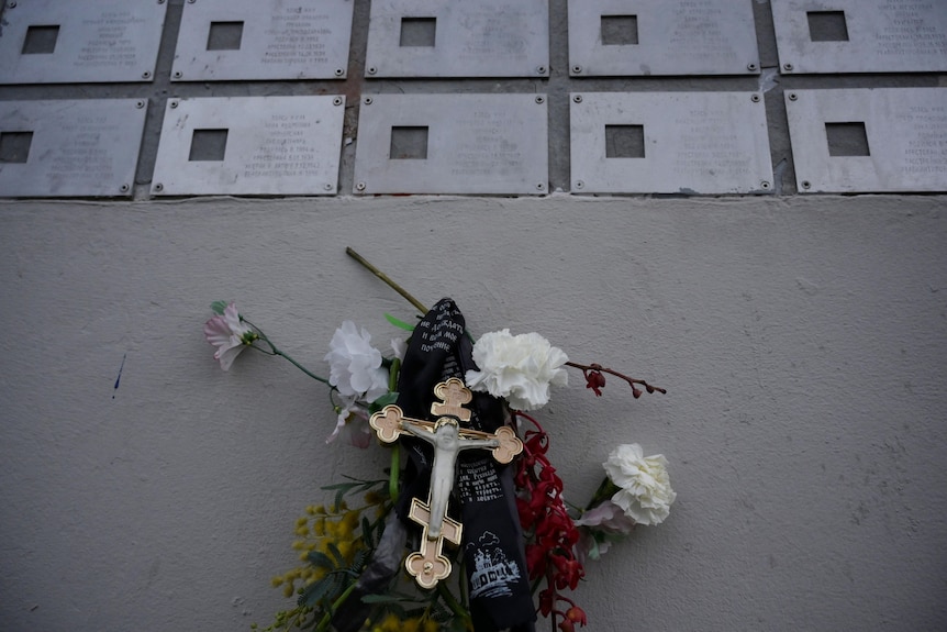 Flowers and a cross under metal plaques.