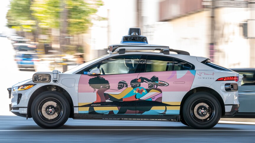 A colourful autonomous taxi with no driver speeds through the streets of San Francisco.