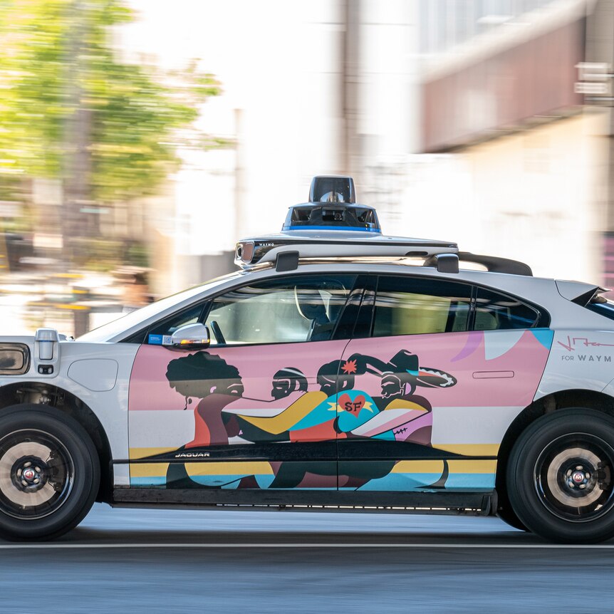 A colourful autonomous taxi with no driver speeds through the streets of San Francisco.
