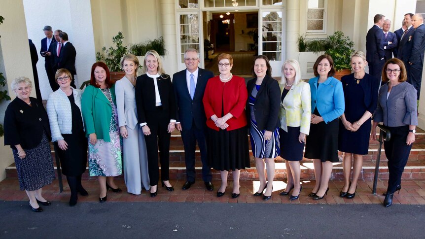 Scott Morrison stands in the middle of a line of women, with men standing in groups in the background