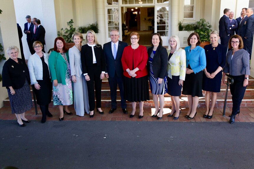 Scott Morrison stands in the middle of a line of women, with men standing in groups in the background
