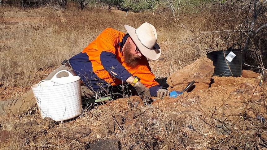 Man digging in earth for artefacts.