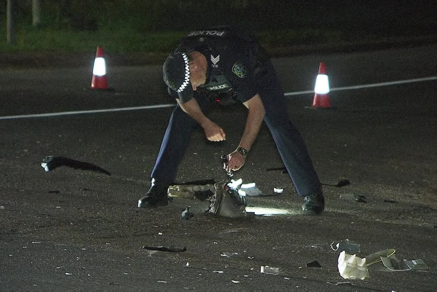 a police officer on the road taking photos of a crash scene