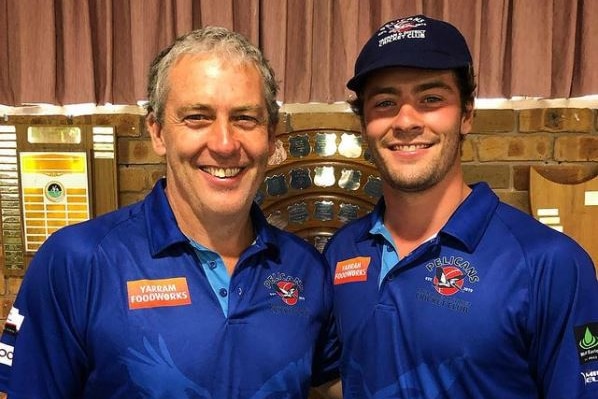Andrew Dunkley and son Josh Dunkley stand with their arms around each other. Josh his wearing a cap. Both wear blue shirts.
