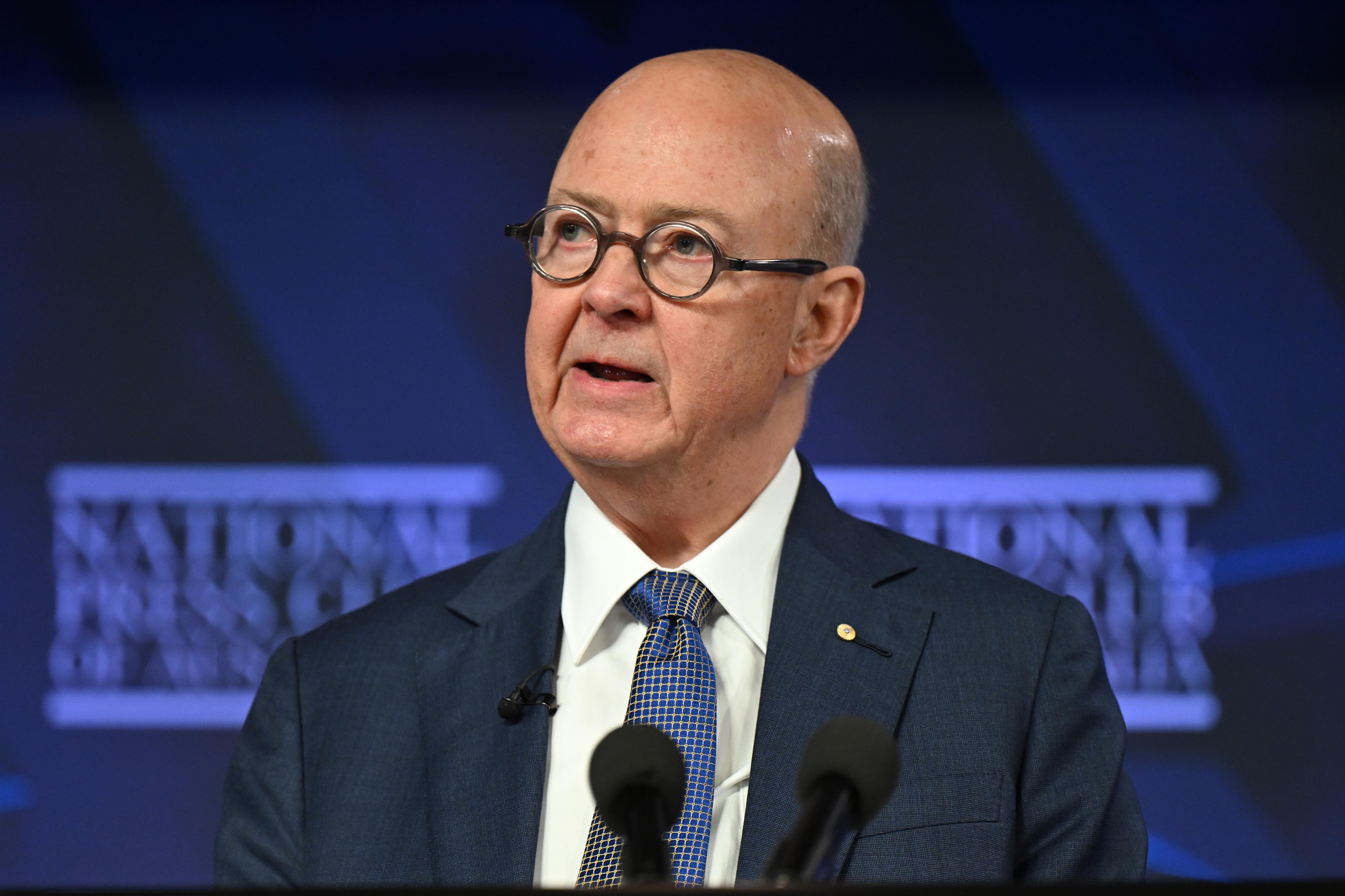 Man with a bald head and glasses looks to the side 
